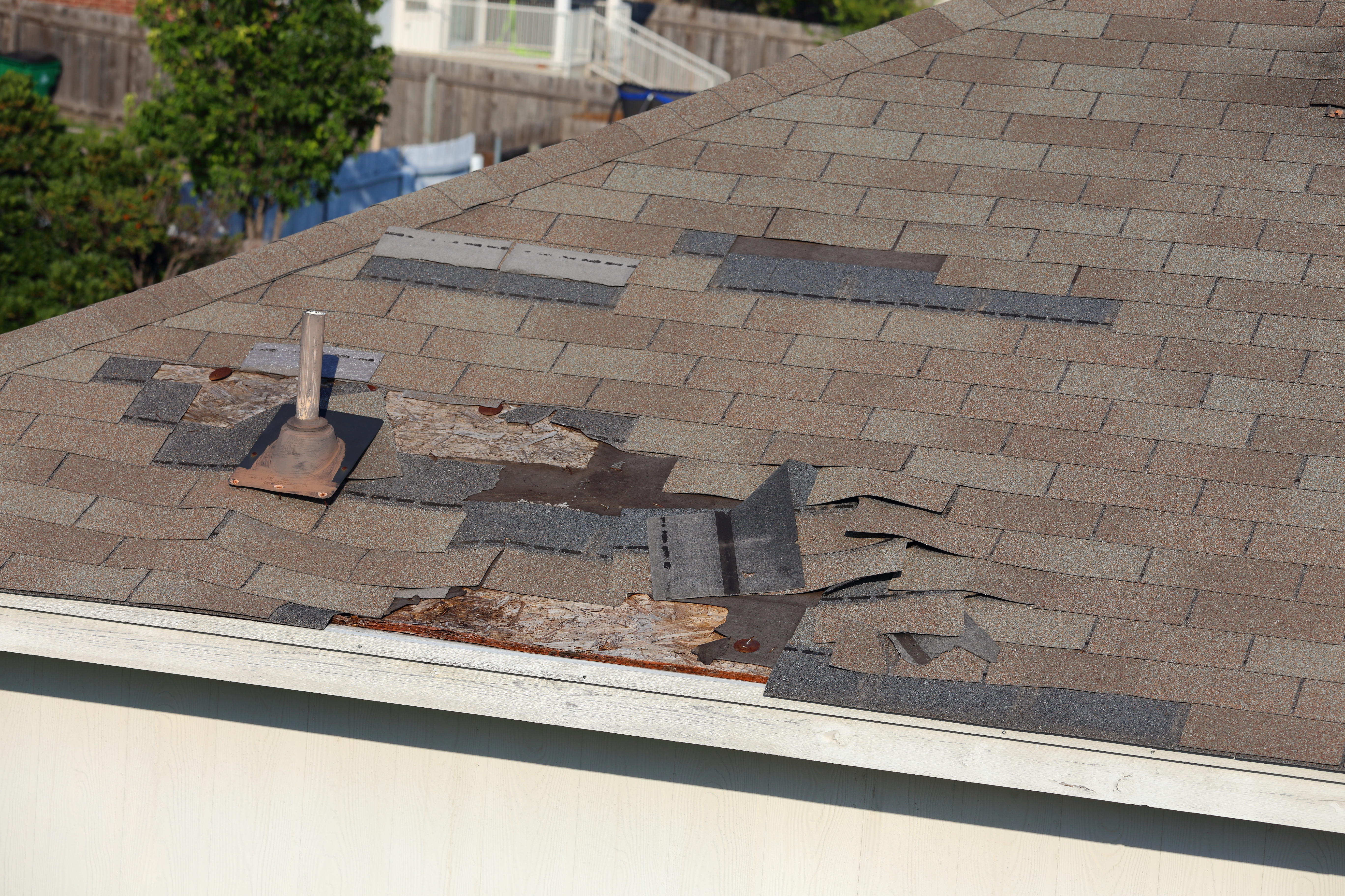 Cypress TX roof with missing and loosened shingles from wind damage
