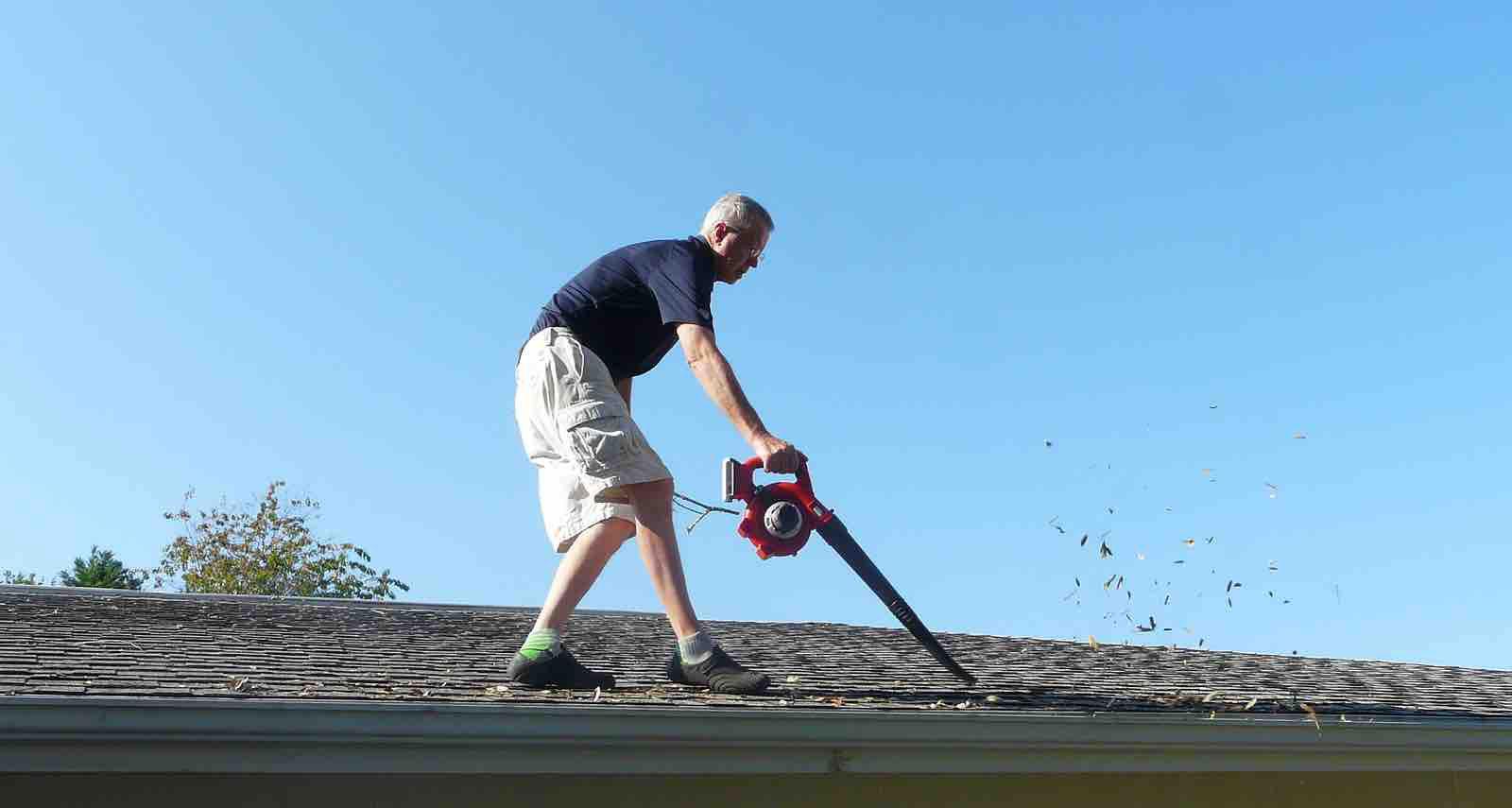 Spring, TX homeowner using a leaf blower to remove debris from his roof