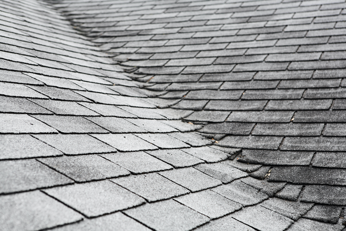 Broken and cracked Houston roof shingles covered in sleet from cold weather roof damage