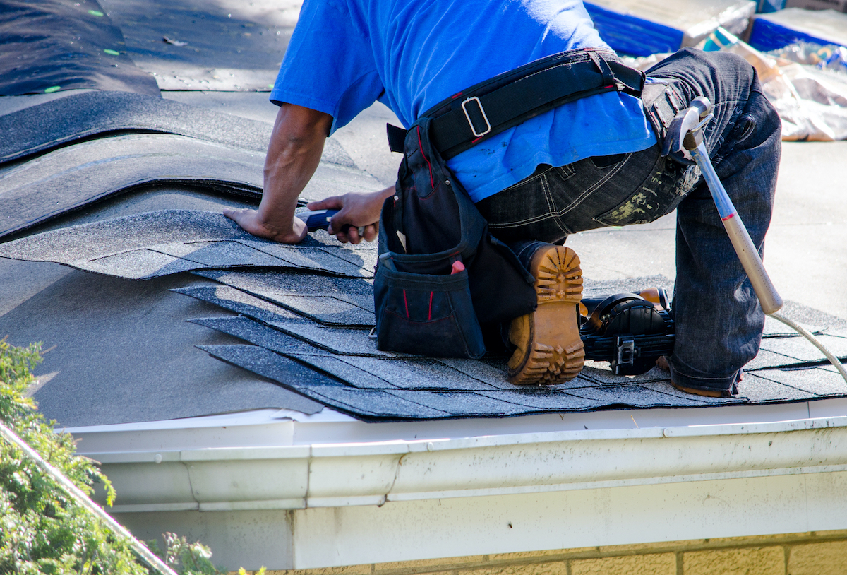 roofing contractor laying down new roof shingles for spring, texas roof replacement