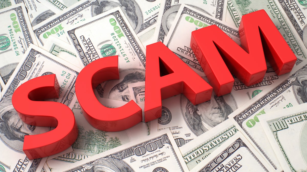 image of the word &quot;scam&quot; on a pile of money