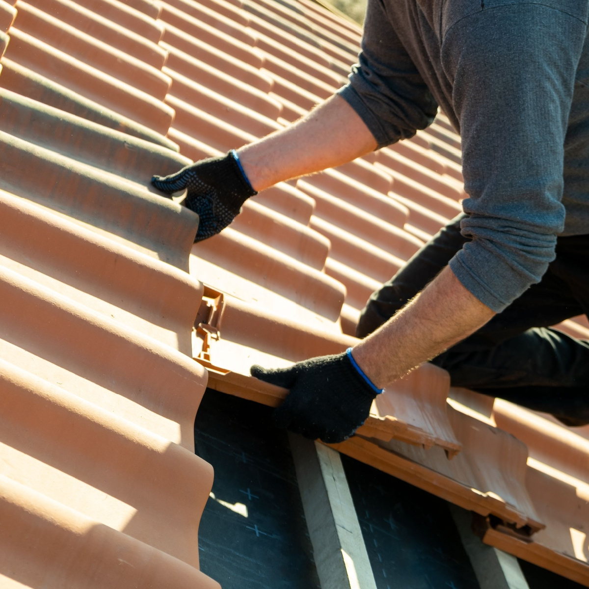 A roofer replacing shingles