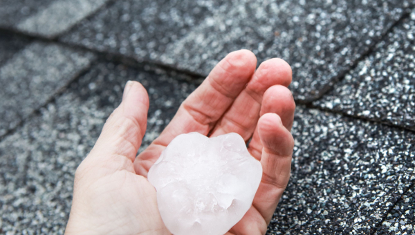 Houston roofer holding a hailstone that caused Sienna hail damage
