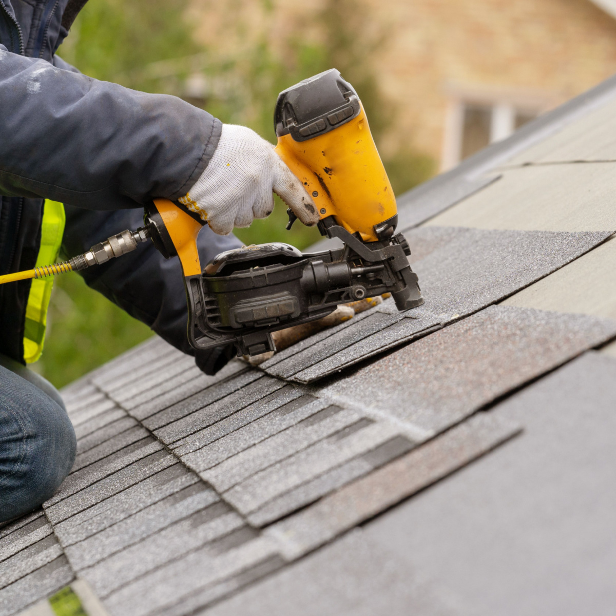A roofer nailing down shingles