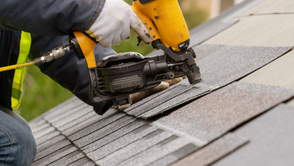 A roofer nailing down shingles